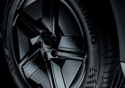 Close-up of a black car wheel with Kumho tyre, featuring geometric patterned rim design.