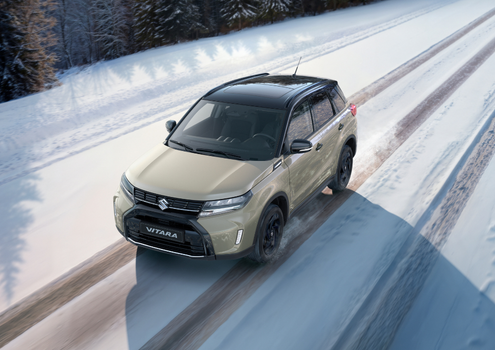 SUV driving on a snow-covered road, surrounded by trees.